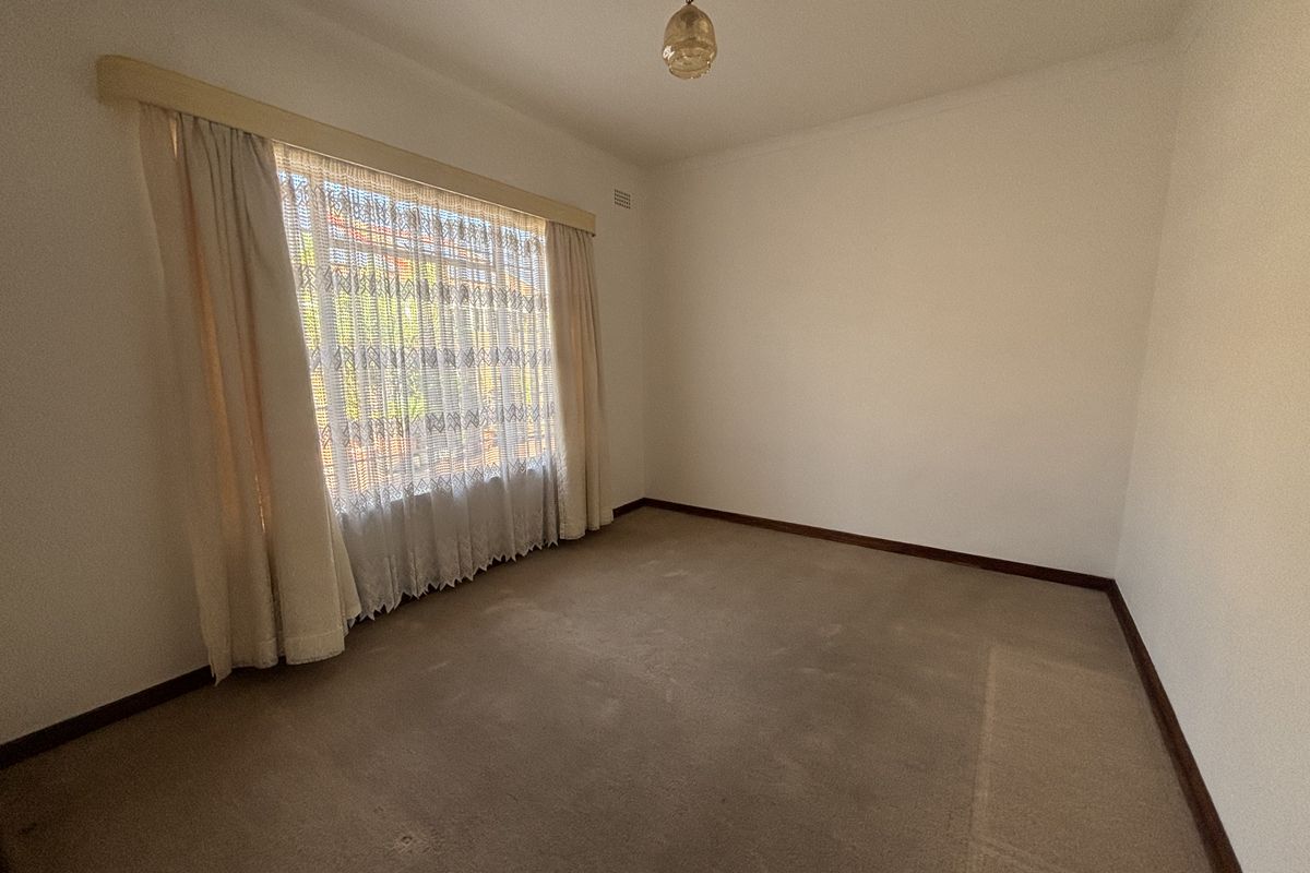 An empty bedroom featuring neutral walls, timber skirting boards, and carpet flooring, offering a blank canvas for potential updates or staging.