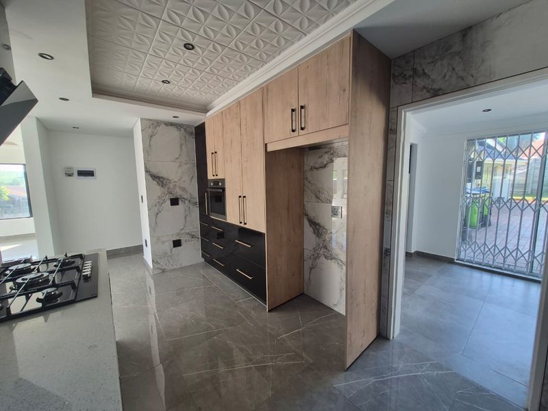 Modern kitchen featuring high-end marble-look finishes, sleek two-tone cabinetry, built-in oven, gas hob, and large-format porcelain floor tiles.