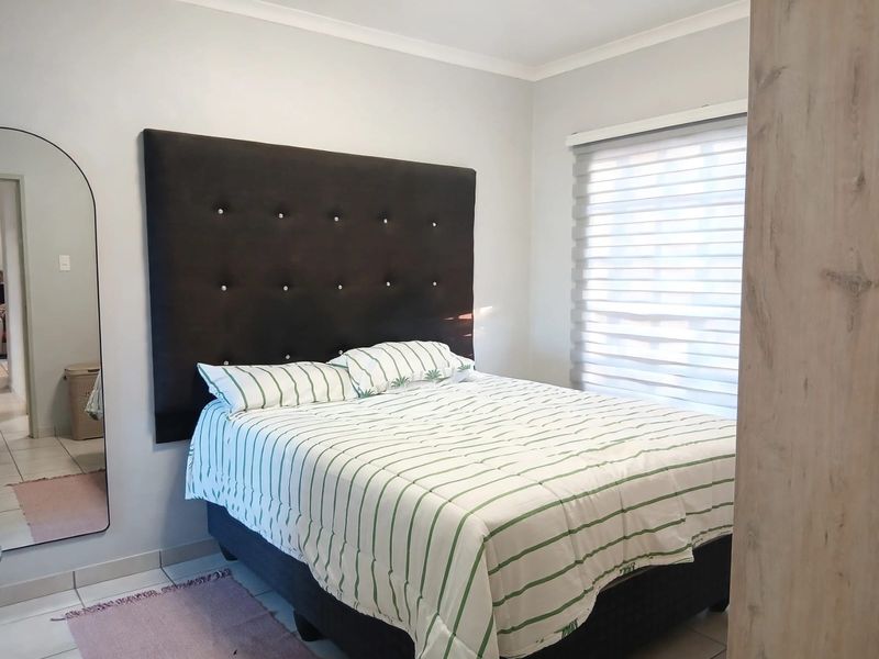 A well-maintained bedroom featuring neutral wall finishes, tiled flooring, and modern roller blinds, providing a clean and comfortable living space.