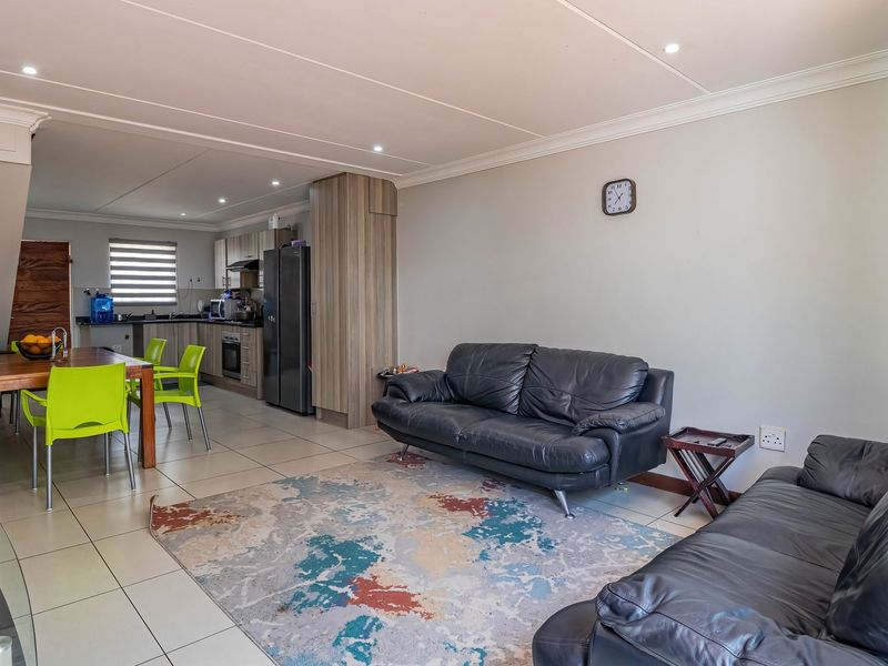 An open-plan living and dining area featuring tiled floors, recessed lighting, and a modern kitchen with built-in cabinetry and appliances.