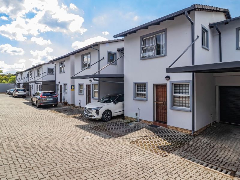 A row of modern townhouse units featuring paved driveways, integrated carports, and secure garage access in a well-maintained residential complex.