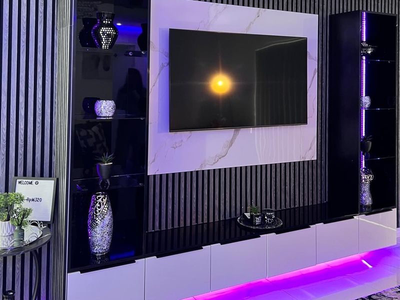 Modern living room featuring a custom built-in media unit with integrated LED lighting, slatted wall paneling, and a marble-effect feature wall.