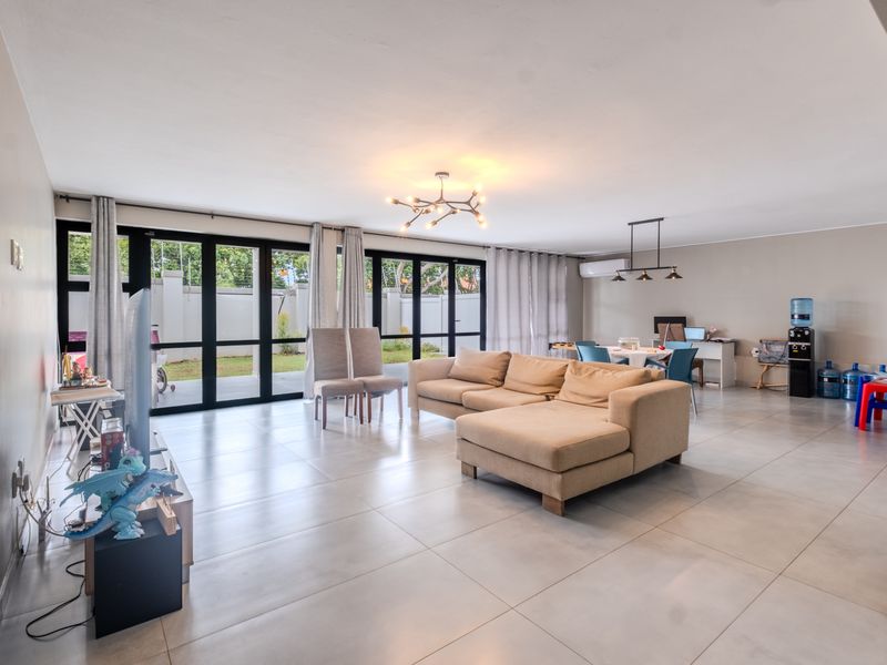 Spacious open-plan living and dining area featuring large black-framed glass sliding doors that provide abundant natural light and seamless access to the outdoor space.