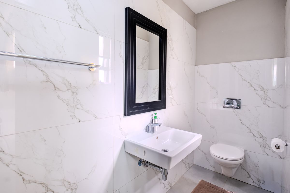 Modern bathroom featuring marble-look wall tiles, a wall-mounted basin with chrome mixer tap, and a wall-mounted toilet with concealed cistern.