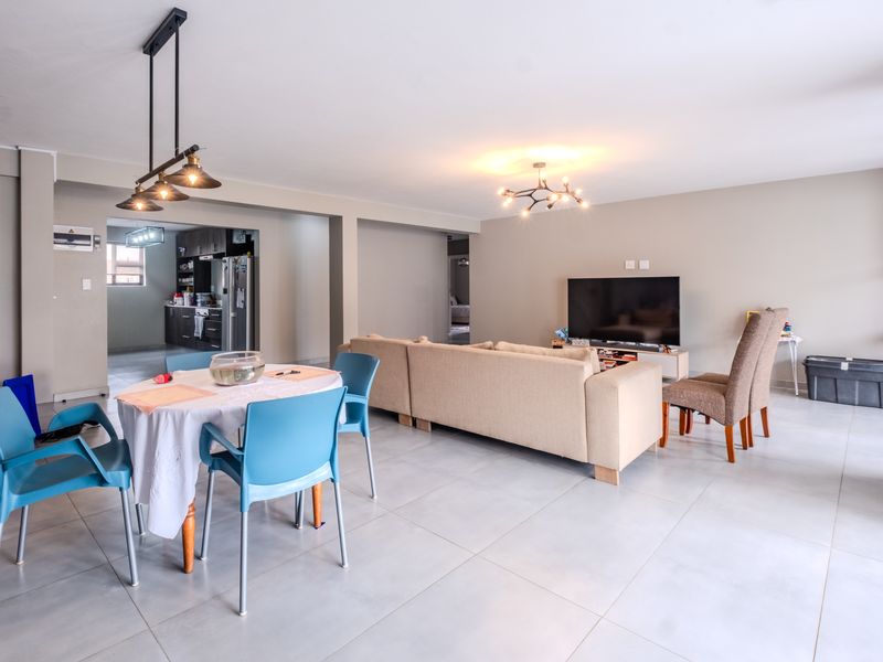 Spacious open-plan living and dining area featuring neutral tiled flooring, modern pendant lighting, and a seamless transition into the adjacent kitchen space.