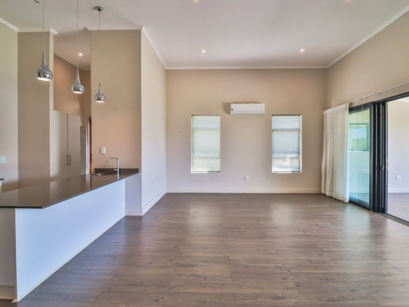 Spacious open-plan living area featuring modern kitchen island, laminate flooring, split-system air conditioning, and large sliding doors leading to an outdoor space.