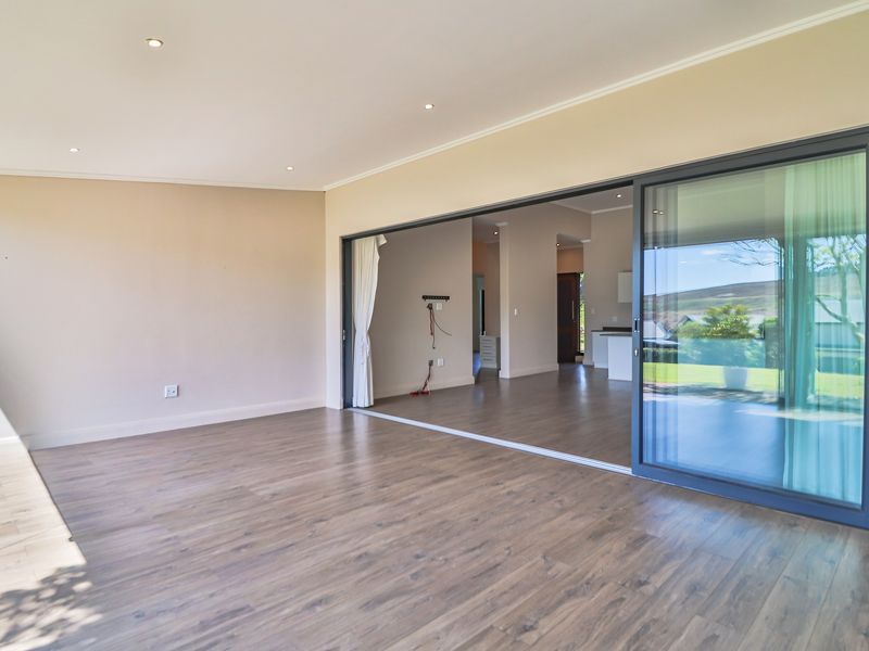Spacious, light-filled living area featuring modern laminate flooring, recessed downlighting, and expansive sliding glass doors that provide seamless access to the outdoor space.