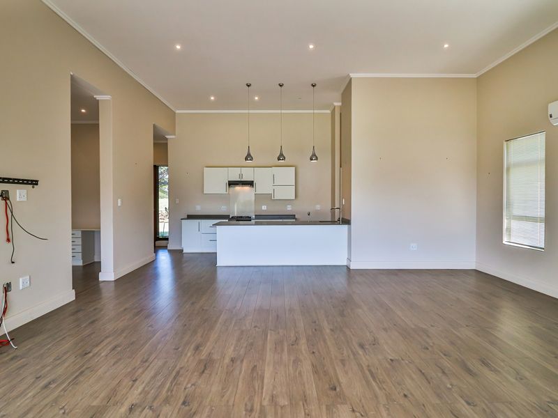 Spacious open-plan living and kitchen area featuring modern laminate flooring, recessed lighting, a functional kitchen island, and a wall-mounted air conditioning unit.