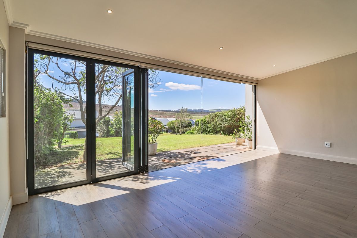 Spacious, light-filled living area featuring modern laminate flooring and large bi-fold doors that open onto a private garden patio.