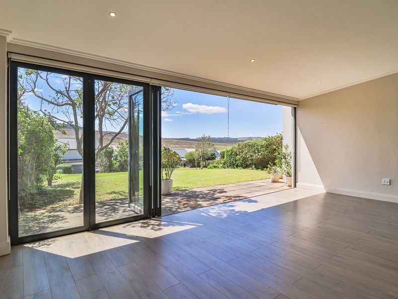Spacious, light-filled living area featuring modern laminate flooring and large bi-fold doors that open onto a private garden patio.