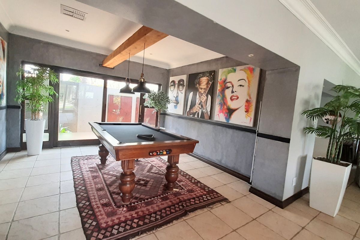 Spacious living area featuring tiled flooring, exposed timber ceiling beams, and large sliding glass doors providing natural light and access to the outdoors.