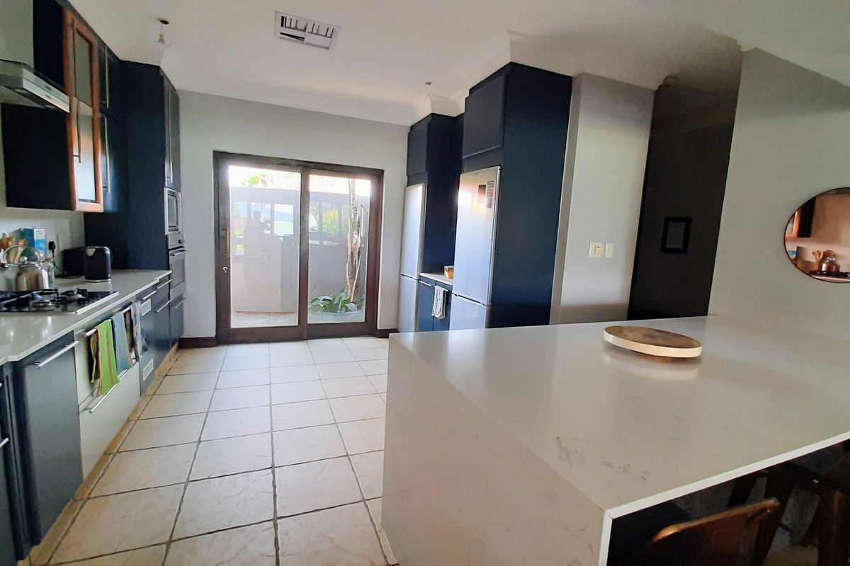 Modern kitchen featuring dark blue cabinetry, stone countertops, a central island, and direct access to the outdoor area through sliding glass doors.