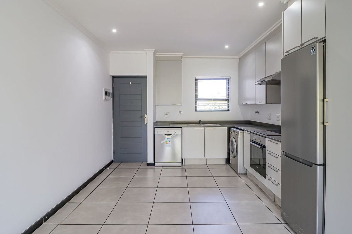 A clean, modern kitchen featuring neutral cabinetry, tiled flooring, integrated appliances, and recessed lighting, offering a functional and well-maintained space.