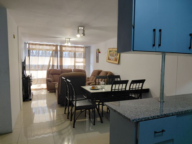 Open plan living and dining area featuring tiled flooring and a functional kitchen with granite countertops.