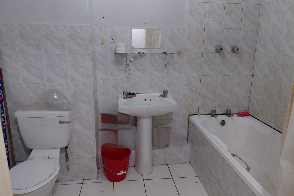 A dated bathroom featuring a pedestal basin, toilet, and bathtub with tiled walls and flooring, requiring cosmetic updates to modernize the space.