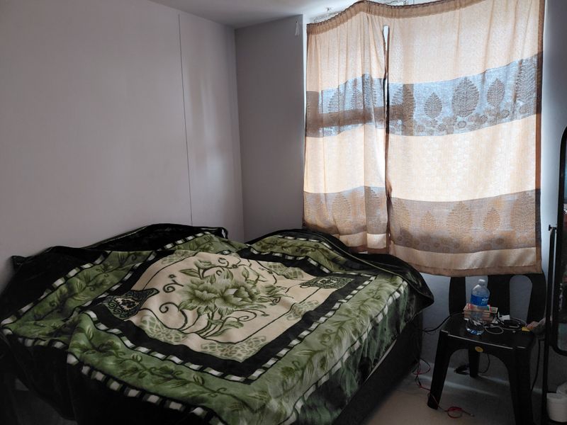 A standard bedroom featuring a window with installed curtain rails, providing natural light to the space.