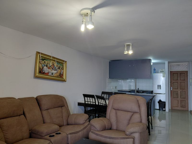 Open plan living and dining area featuring tiled floors and a functional kitchen space with built-in cabinetry and counter.