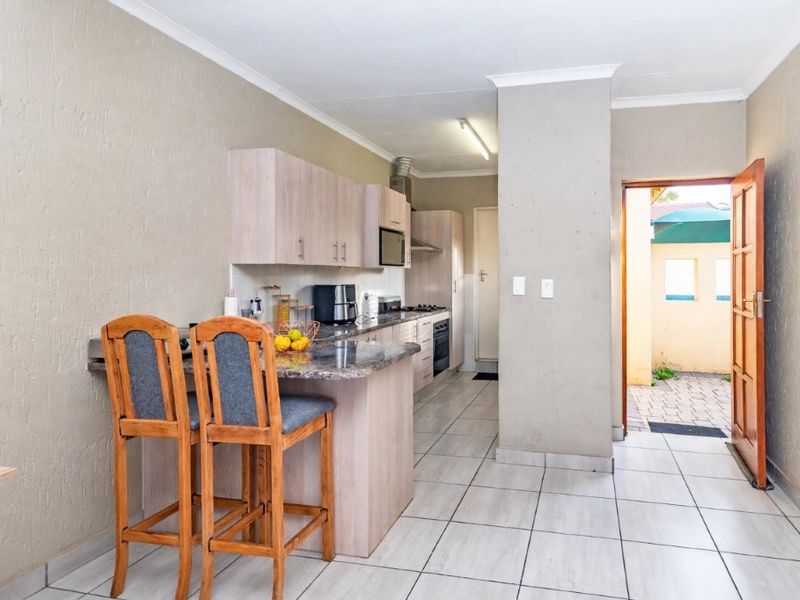 Functional kitchen featuring built-in cabinetry, granite countertops, integrated oven and hob, with direct access to an outdoor area.