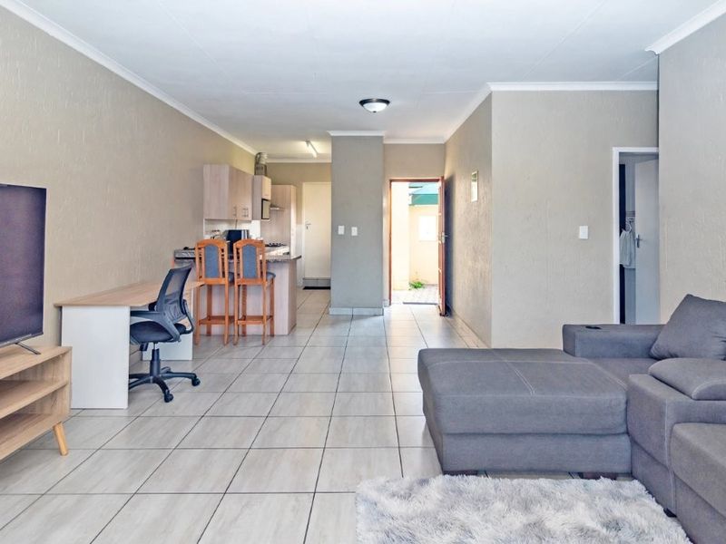 Open plan living area featuring tiled flooring, a functional kitchen with breakfast bar, and direct access to an exterior doorway.