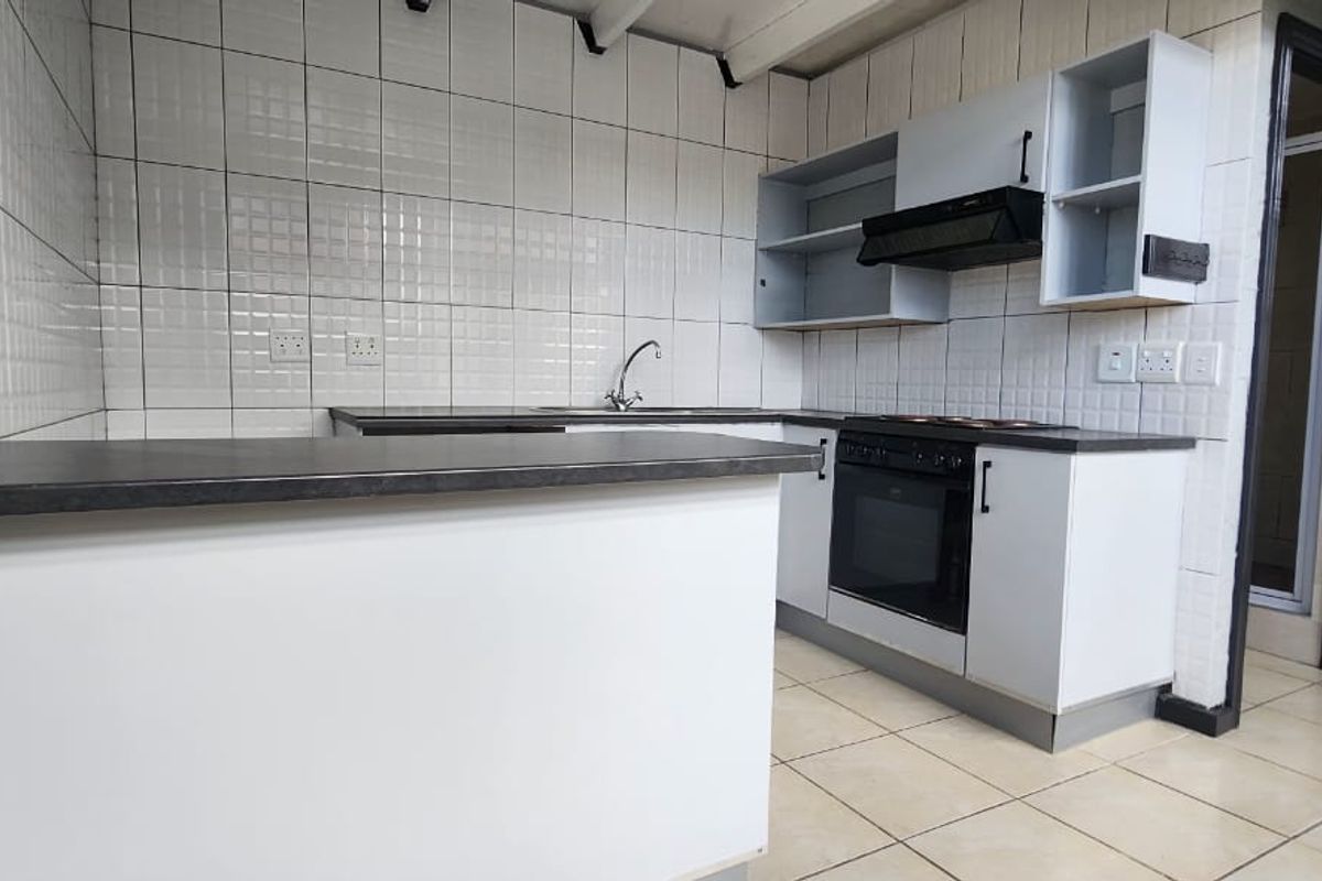 A functional kitchen featuring built-in cabinetry, an oven with extractor fan, tiled backsplash, and laminate countertops, ready for modernization.