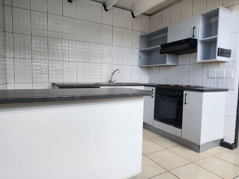 A functional kitchen featuring built-in cabinetry, an oven with extractor fan, tiled backsplash, and laminate countertops, ready for modernization.