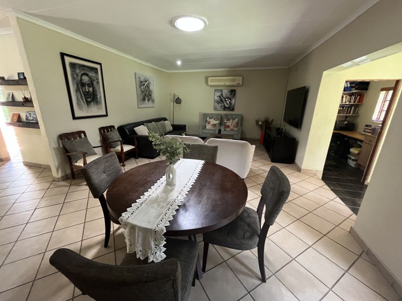 Open-plan living and dining area featuring tiled flooring, coved cornicing, and a wall-mounted air conditioning unit.