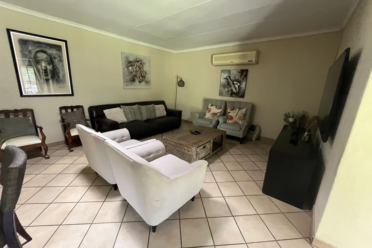 A spacious living room featuring ceramic tile flooring, a wall-mounted air conditioning unit, and coved ceilings, offering a comfortable and functional living space.