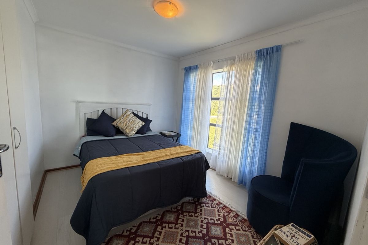 A well-lit bedroom featuring neutral walls, light-toned flooring, and a built-in wardrobe, offering a comfortable and functional living space.