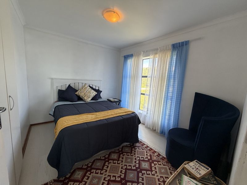 A well-lit bedroom featuring neutral walls, light-toned flooring, and a built-in wardrobe, offering a comfortable and functional living space.