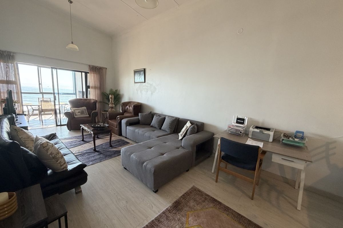 Spacious open-plan living area featuring laminate flooring and large sliding glass doors that provide natural light and access to the balcony.