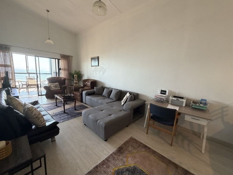 Spacious open-plan living area featuring laminate flooring and large sliding glass doors that provide natural light and access to the balcony.