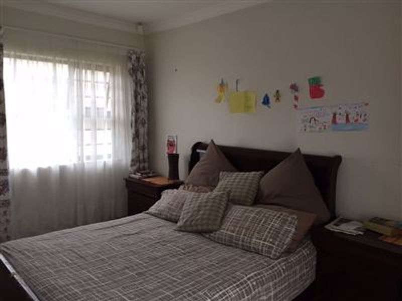 A standard bedroom featuring a window with security bars and decorative cornice detailing.