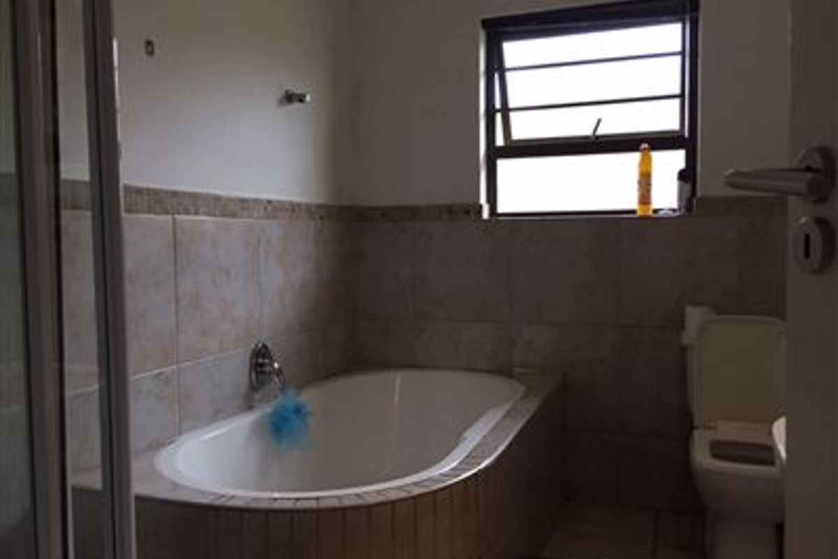 A functional bathroom featuring a built-in bathtub, tiled wall finishes, and a standard toilet, providing a practical space for daily use.