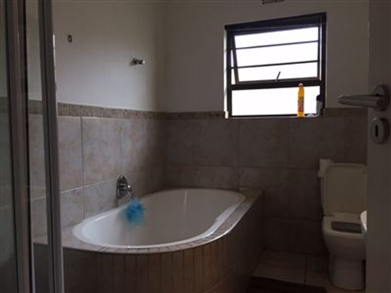 A functional bathroom featuring a built-in bathtub, tiled wall finishes, and a standard toilet, providing a practical space for daily use.