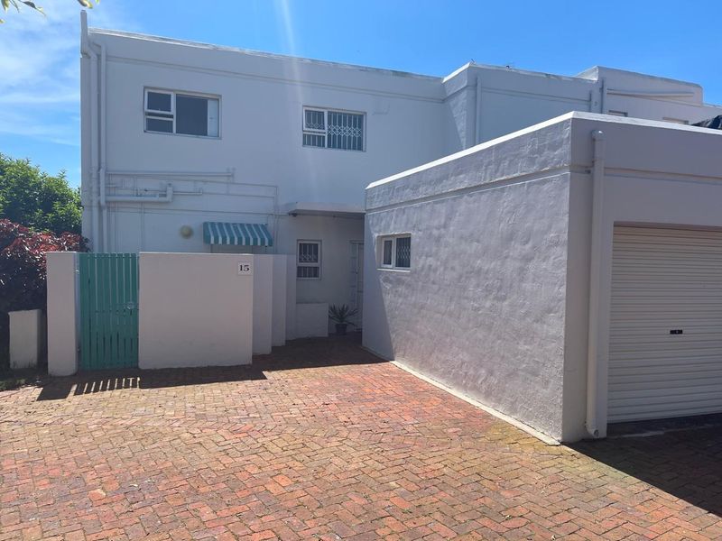 Front exterior view of the townhouse featuring a brick driveway, private entrance gate, and an attached garage with a roller door.