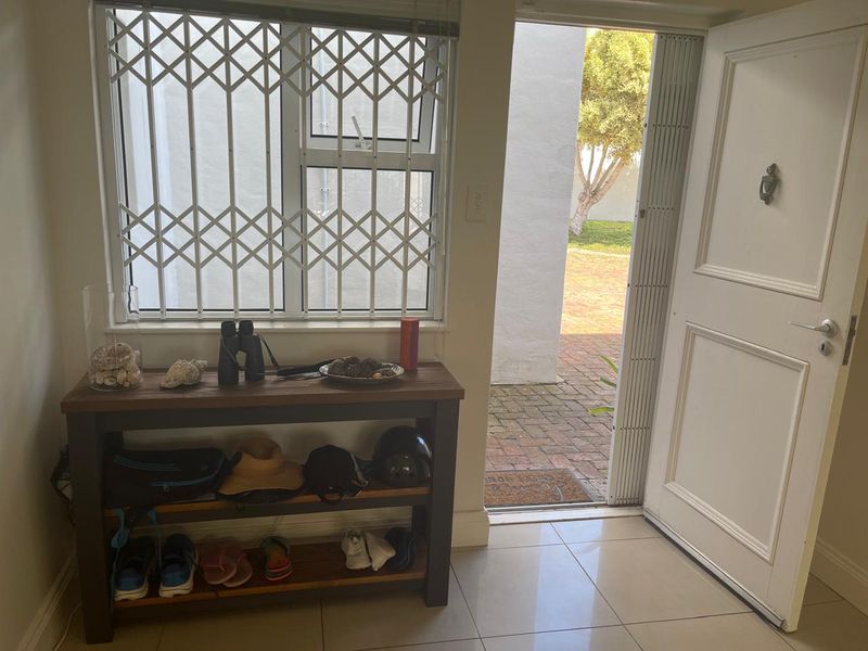 An entrance area featuring tiled flooring, a security gate on the window, and a solid panel door leading to an outdoor paved area.