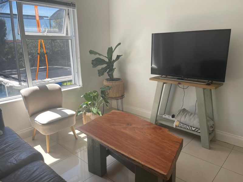 A bright living room featuring neutral tiled flooring and a large window, providing a clean and functional space for relaxation.