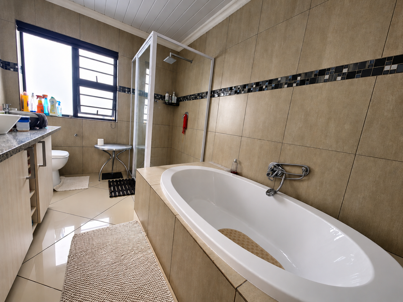 A well-appointed bathroom featuring a built-in vanity, a separate shower enclosure, and a modern bathtub with tiled finishes throughout.