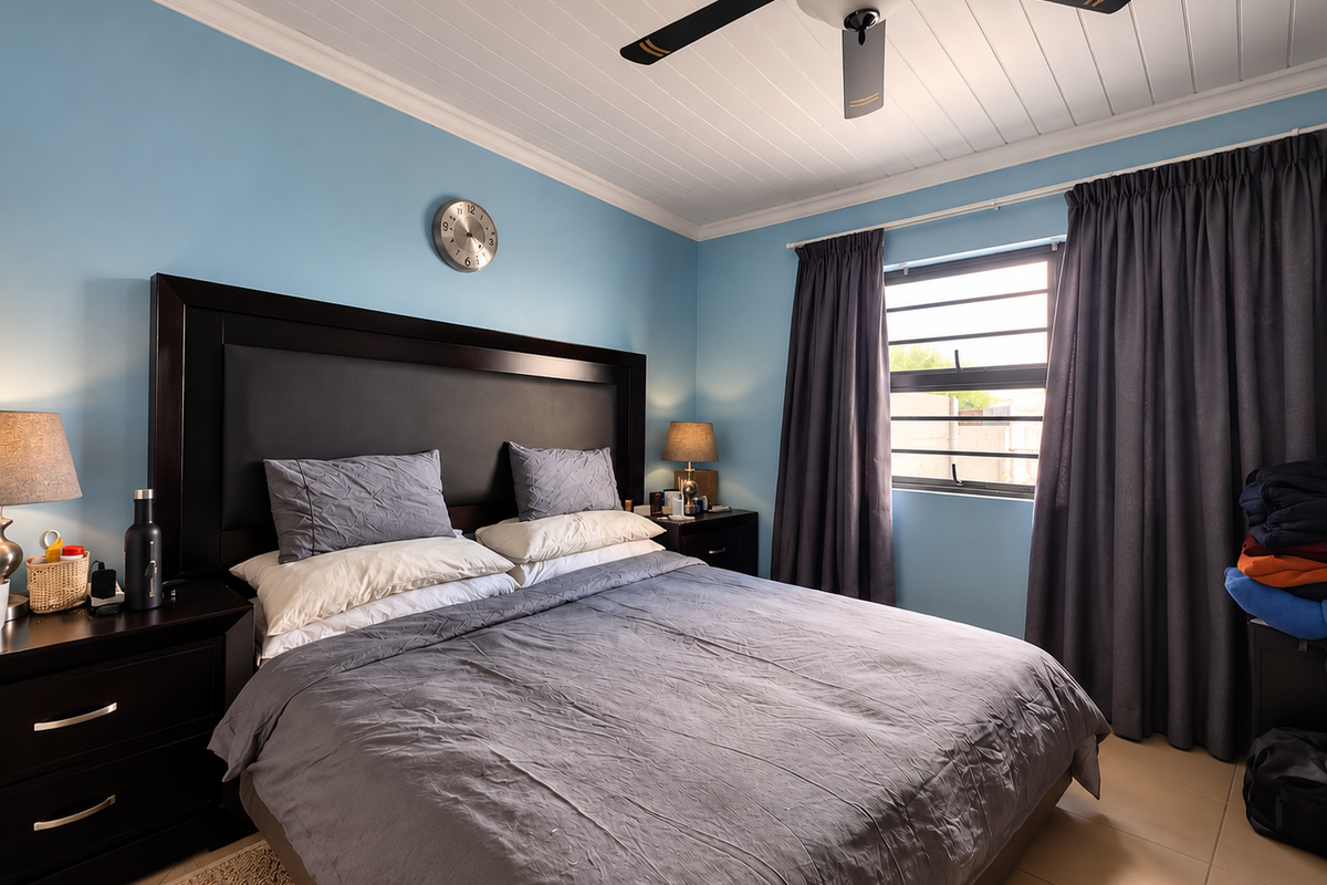 A well-maintained bedroom featuring a tongue and groove ceiling with a fan, tiled flooring, and large windows with dark curtains.