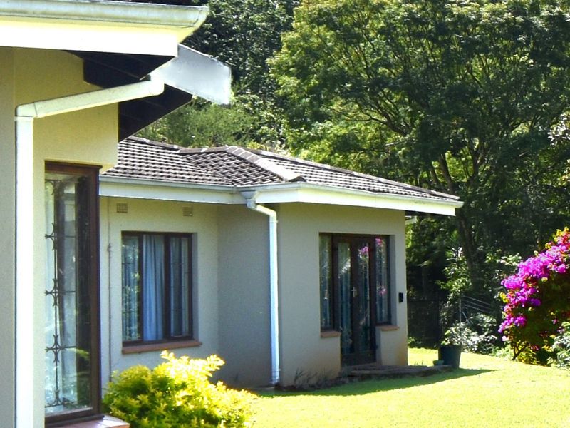 A view of the rear exterior elevation featuring a tiled roof, gutters, and garden access through glass panel doors.