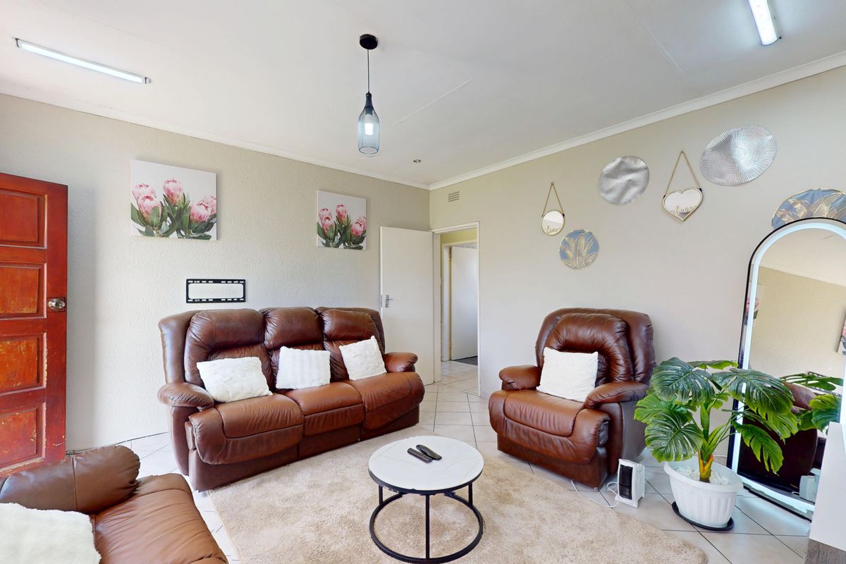 A comfortable living room featuring tiled flooring, a solid timber door, and a mix of pendant and strip lighting.