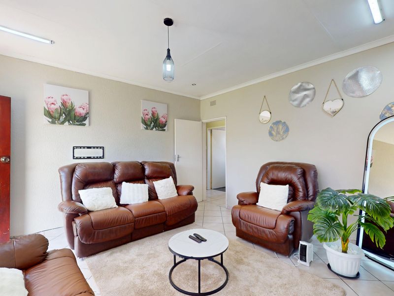 A comfortable living room featuring tiled flooring, a solid timber door, and a mix of pendant and strip lighting.