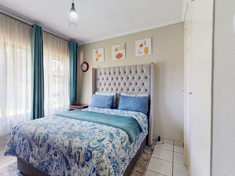 A well-lit bedroom featuring tiled flooring and built-in cupboards, offering a functional and comfortable living space.