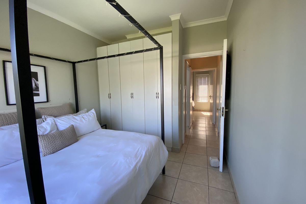 A bedroom featuring tiled flooring, built-in cupboards, and neutral wall finishes, providing a functional and well-maintained living space.