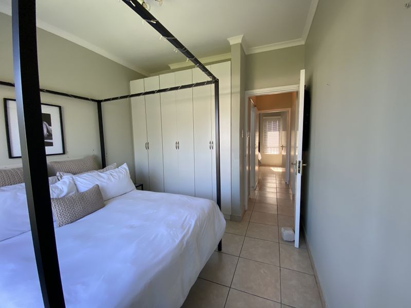 A bedroom featuring tiled flooring, built-in cupboards, and neutral wall finishes, providing a functional and well-maintained living space.