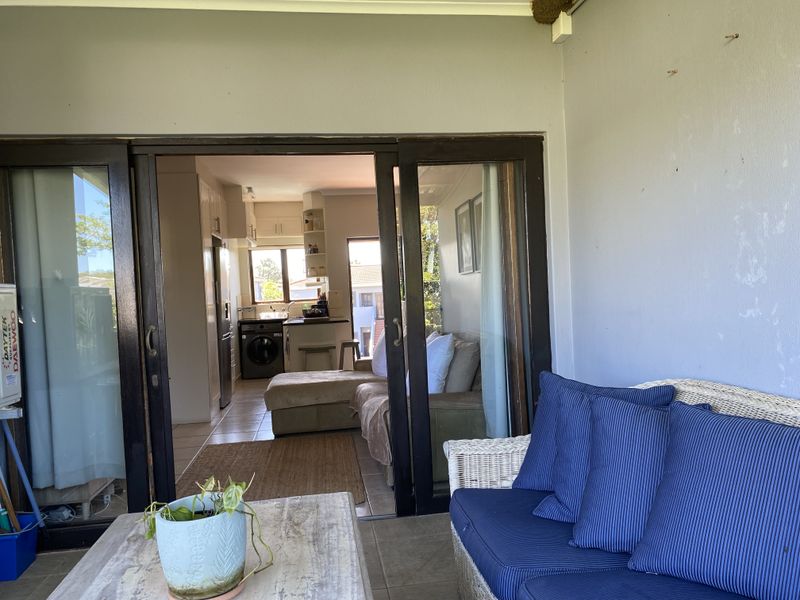 Covered patio area with sliding glass doors leading into an open-plan kitchen and living space.