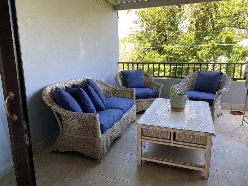A covered balcony featuring tiled flooring and a metal balustrade, providing an outdoor space for relaxation.