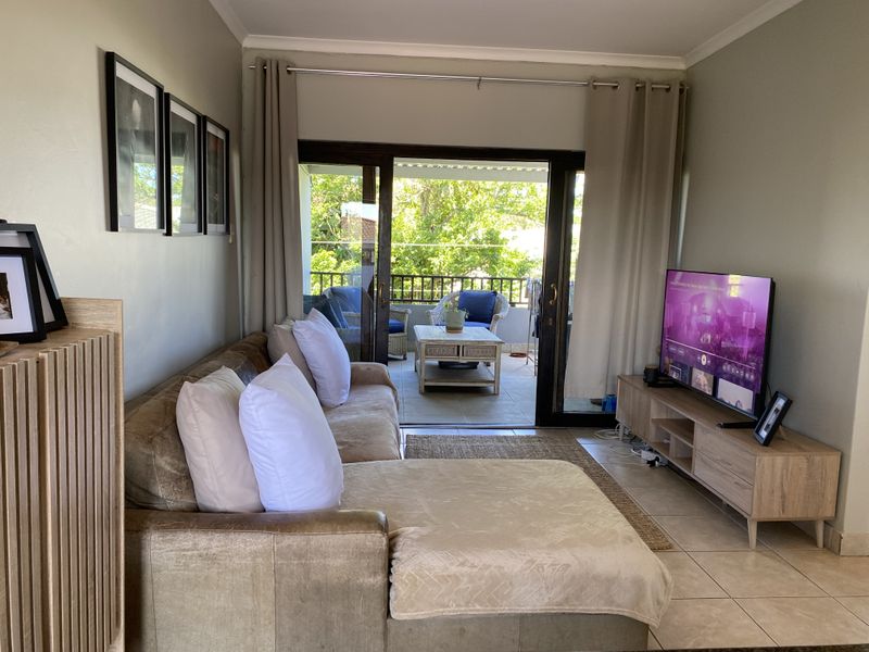 A comfortable living room featuring tiled flooring and large sliding glass doors that provide direct access to an outdoor balcony area.