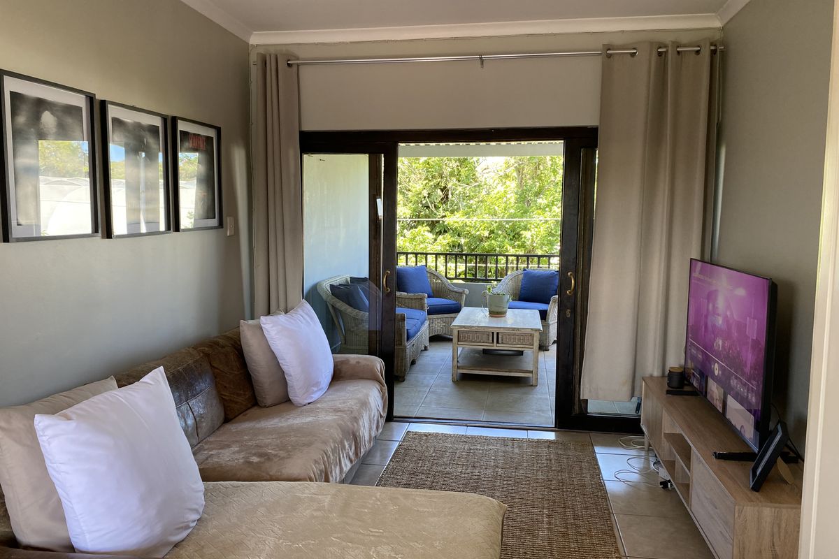 A comfortable living room featuring tiled flooring and large sliding glass doors that open onto a private balcony, providing natural light and outdoor access.
