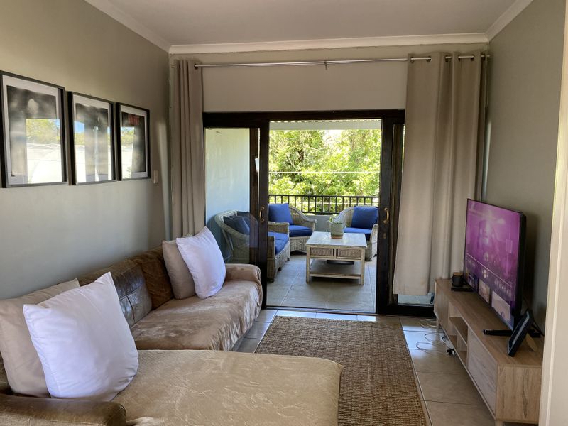 A comfortable living room featuring tiled flooring and large sliding glass doors that open onto a private balcony, providing natural light and outdoor access.